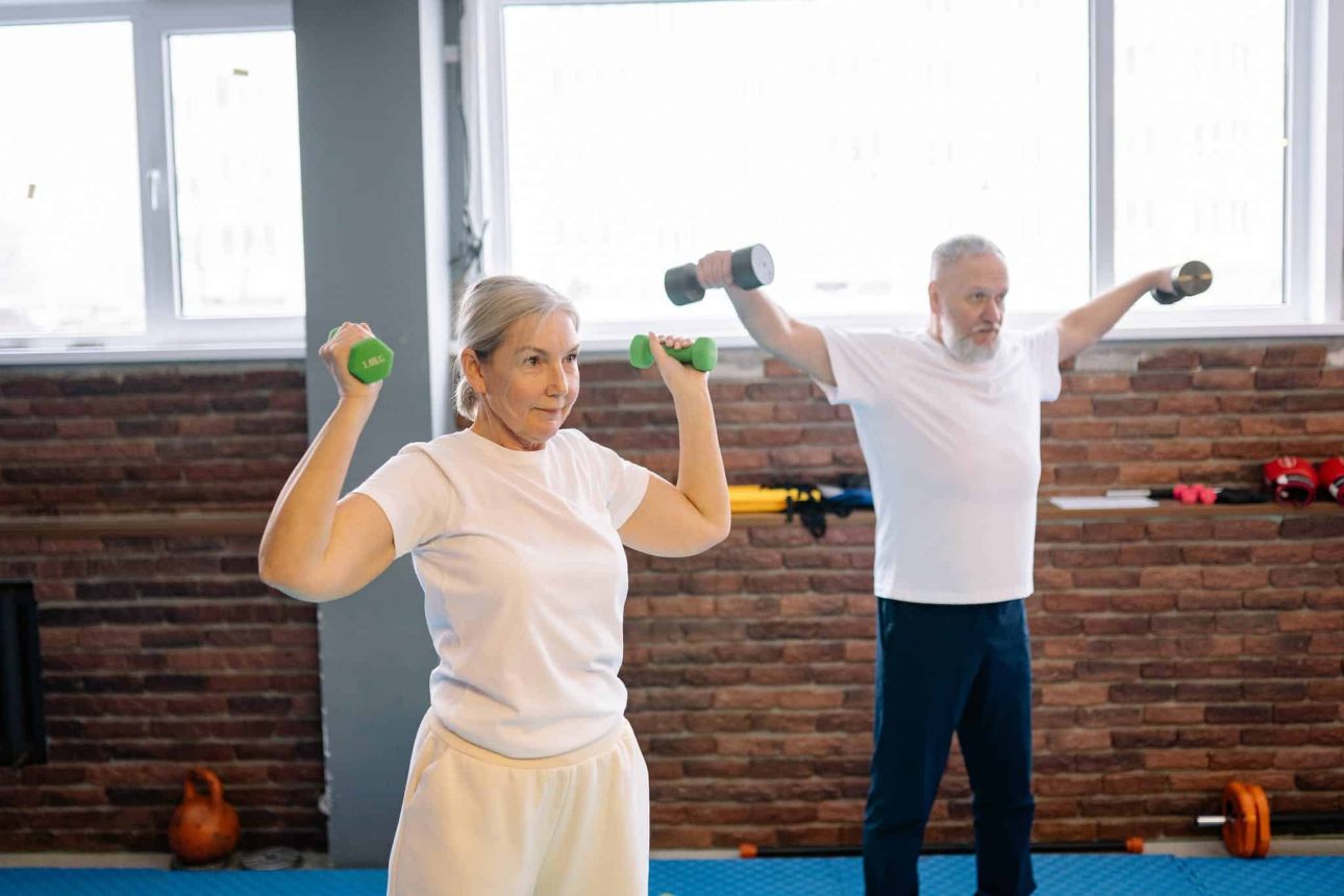 An elderly couple doing exercise by lifting Dumbbells
