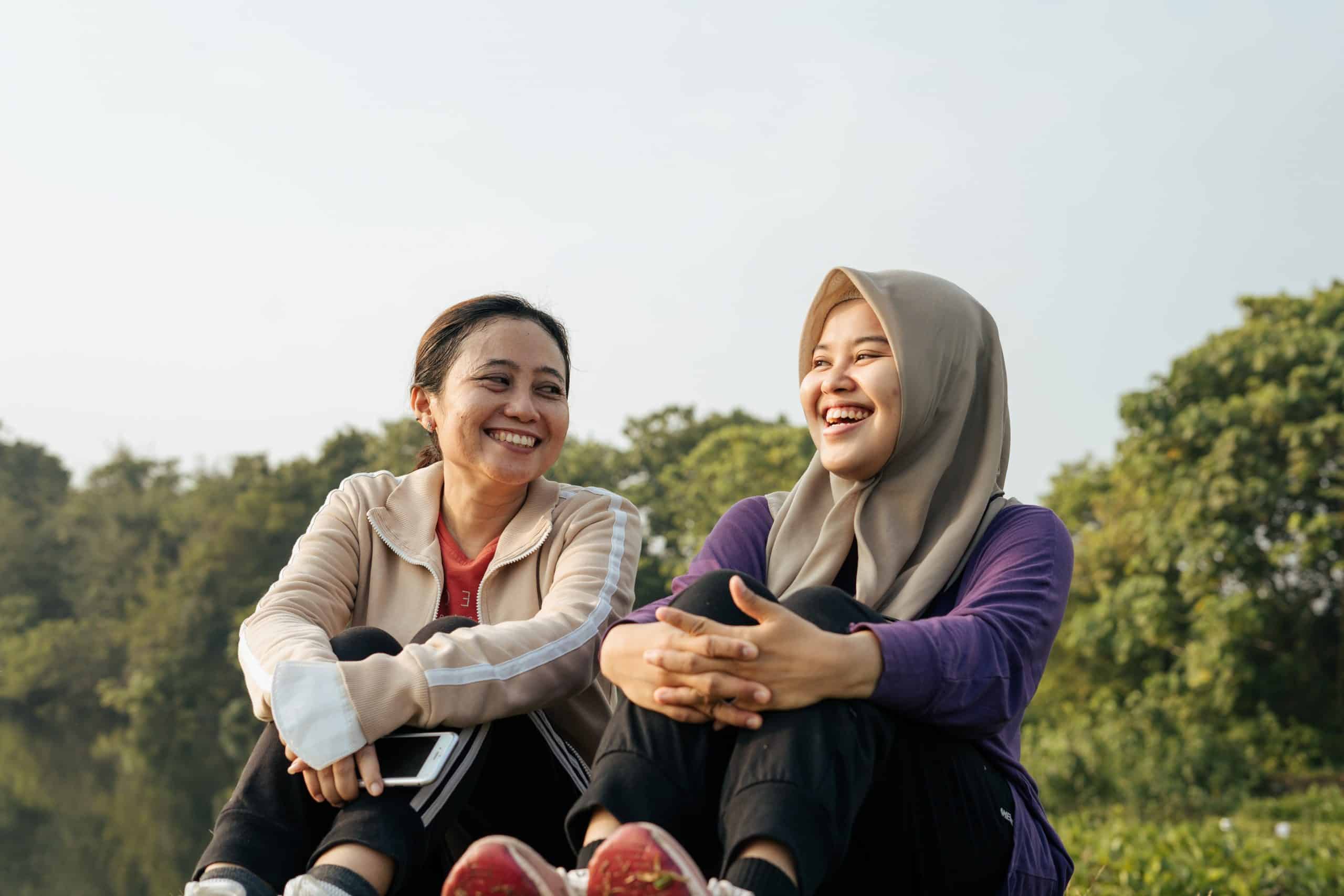 two malay women sitting and chatting happily outdoors