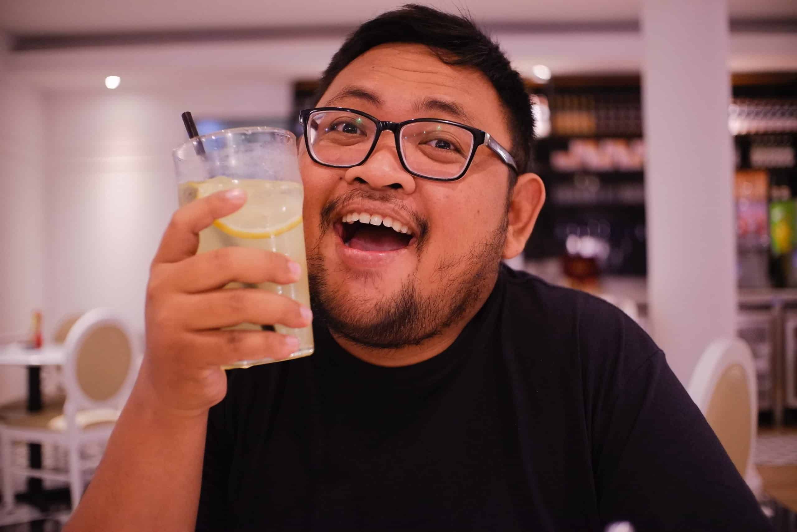 young guy smiling with a drink in hand